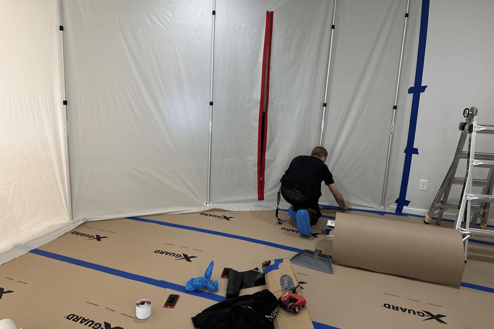 Man kneeling on brown paper floor covering, preparing installation in a room.