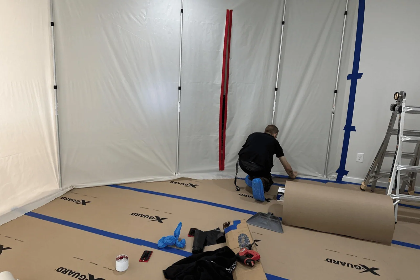 Man kneeling on brown paper floor covering, preparing installation in a room.