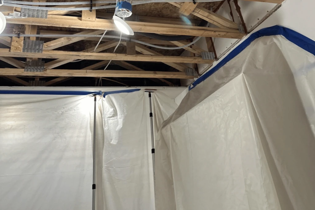 Restoration work area with white containment tarps and open ceiling.