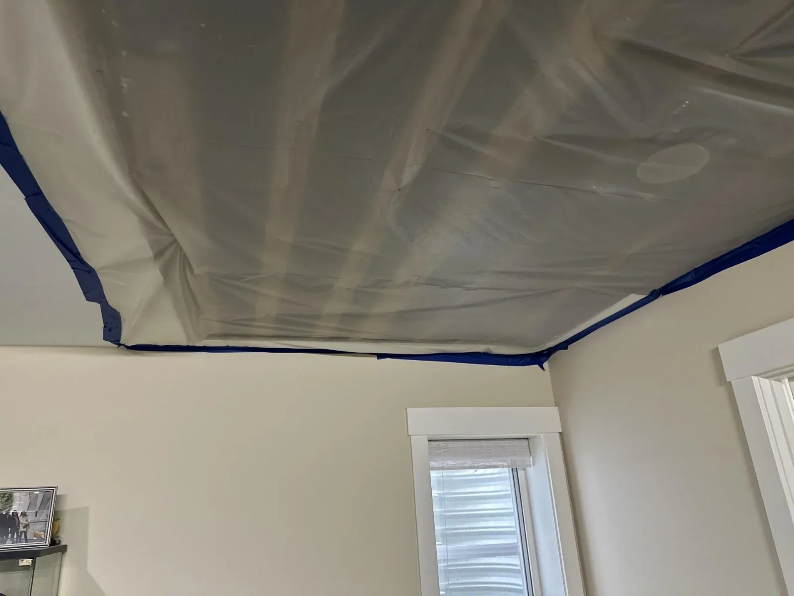 Plastic sheeting secured with blue tape below a ceiling work area