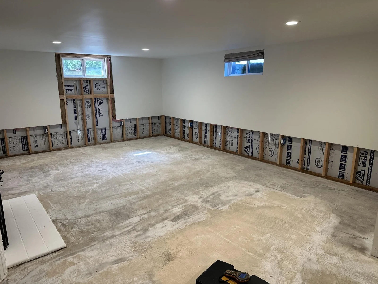 Room with lower drywall removed to expose wall framing and the floor uncovered